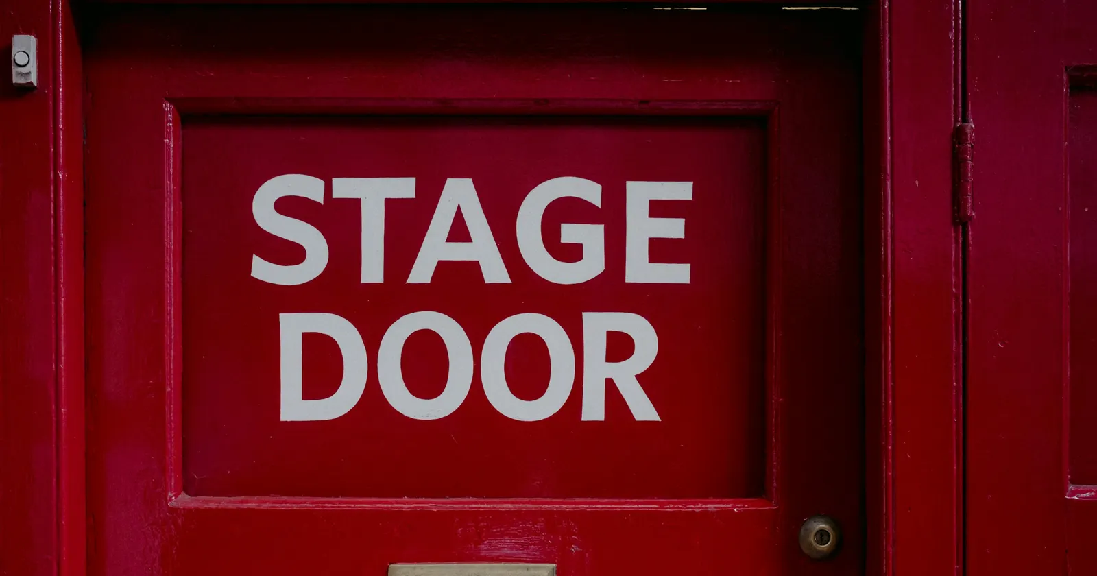 Une porte d'entrée des artistes peinte en rouge, avec l'inscription STAGE DOOR en grandes lettres blanches