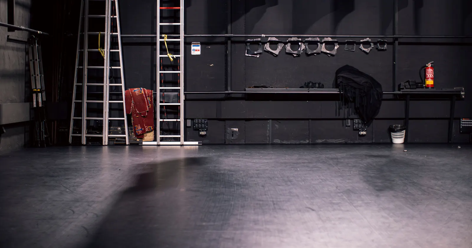 Un escenario de teatro vacío, dos escaleras contra la pared negra y material de montaje
