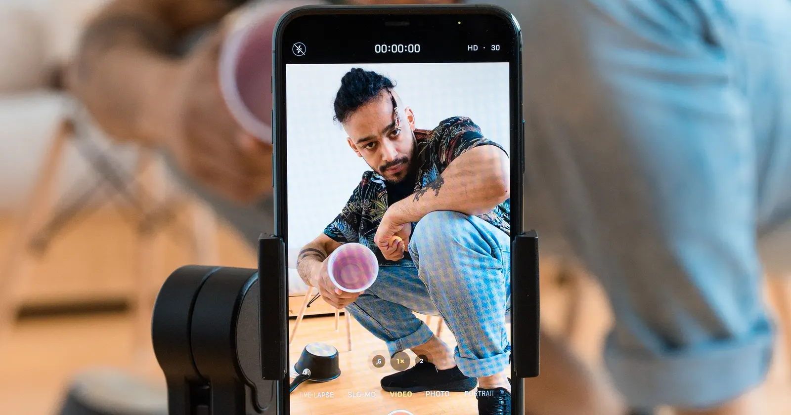 Un téléphone sur trépied filme un comédien dans son salon